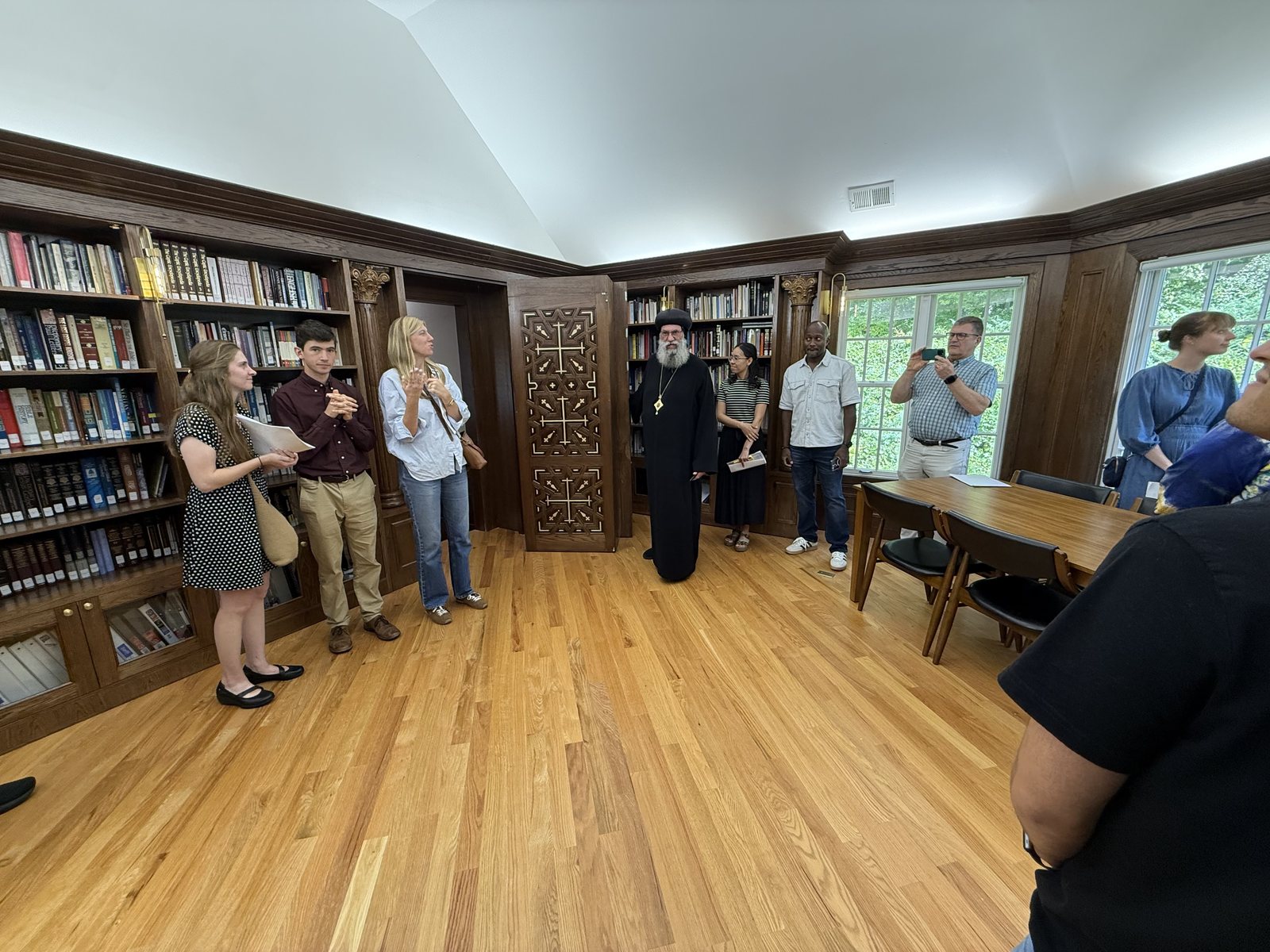 Visitors gather in the museum reading room, with Bishop Suriel by a carved wooden door